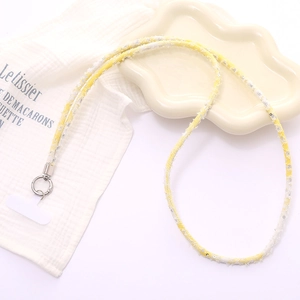Detail of yellow and white woven phone lanyard with sequins and silver metal ring