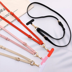 Adjustable leather phone crossbody straps in black, red, pink, and beige with gold buckles