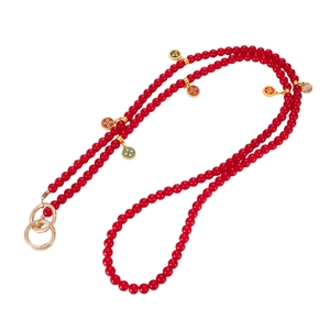 Detail view of long beaded phone chain with red glass beads and floral enamel charms