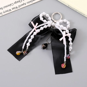 Detail of elegant black silk bow charm with white pearl chains and multi-colored beads