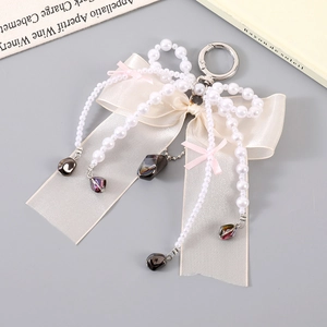 Elegant ribbon bow and pearl bead bag charm with a silver clasp for stylish accessories