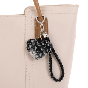 Gros plan d'un pendentif cœur en denim usé avec fermoir mousqueton argenté sur un sac