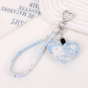 Détail d'un porte-clés cœur en jean bleu clair avec paillettes et crochet en métal cœur