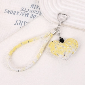 Détail d'un pendentif cœur à paillettes jaunes avec dragonne et fermoir cœur en argent