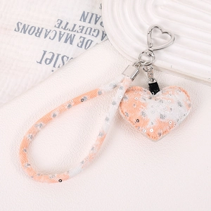 Détail d'un charme coeur orange en denim avec paillettes et dragonne tissée sur fermoir