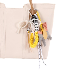Braided phone charm with gray leather pegasus and yellow cord on a leather tote bag