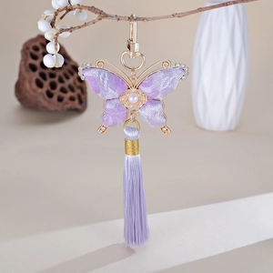 Détail du pendentif papillon fait main en soie violette avec pompon sur une branche