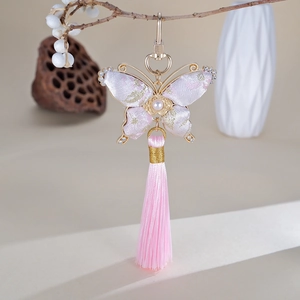 Détail d'un bijou de sac papillon fait main en brocart rose avec strass et gland en soie
