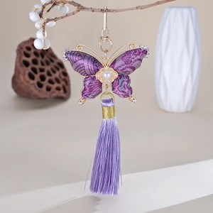 Détail d'un pendentif papillon violet fait main avec bords en cristal et pompon