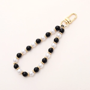 Close-up of black and white beaded charm with gold spacers and metallic lobster clasp