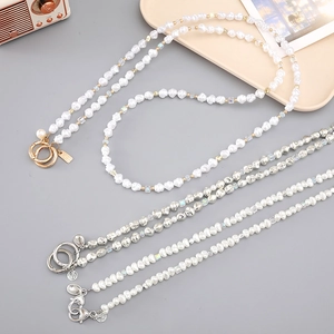 Crossbody pearl phone strap with metal beads and Fu character charm on grey background