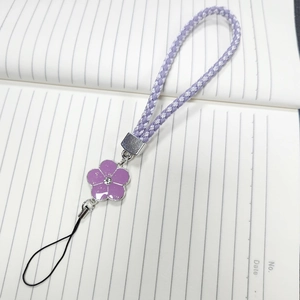 Detail of hand-woven purple flower phone charm with enamel petals and rhinestone center