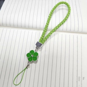 Close-up of bright green braided phone lanyard with a silver flower charm and sparkling diamond