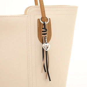 Sac fourre-tout en cuir crème avec pompon tressé et breloque en métal argenté en cœur