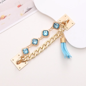 Detail of gold alloy chain with light blue gemstones and leather tassel accessory