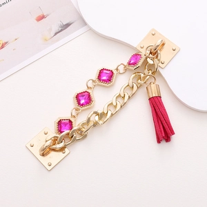 Close-up of golden DIY chain accessory with pink gemstones and tassel for phone cases
