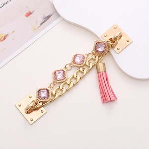 Golden handbag chain strap with pink gemstones and tassel decoration on white background