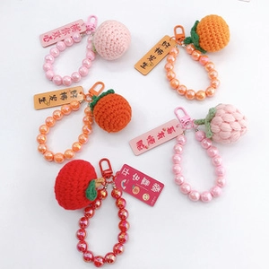 Detailed close-up of handmade crochet fruit keychains with colorful bead chains and gift tags