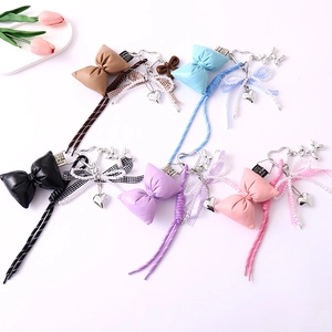 Five assorted colors of leather bow bag charms with pearls and tassels on white background