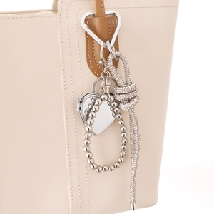 Miroir cœur en strass argenté et pampille nouée sur la poignée d'un sac en cuir chic