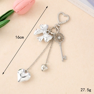 Silver Y2K heart and bow metal keychain with vintage key pendant on soft background