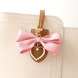 Chic pink satin bow keychain with pearl heart pendant on a luxury beige handbag