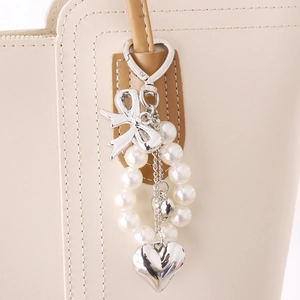 Elegant pearl bow bag charm with a 3D silver heart pendant on a tote handle
