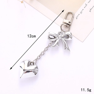 Detailed view of silver bow and heart pendant charm showing 12cm length and 11.5g weight