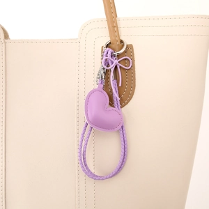 Bijou de sac coeur violet en similicuir avec nœud sur un sac à main beige élégant