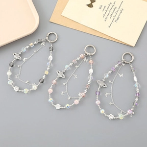 Detail of beaded phone charms with crystal stars, bows, and planetary pendants