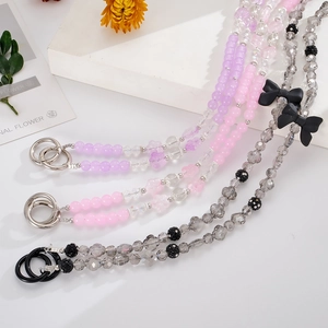 Beaded phone lanyard with grey clover and pink crystal charms on a white display