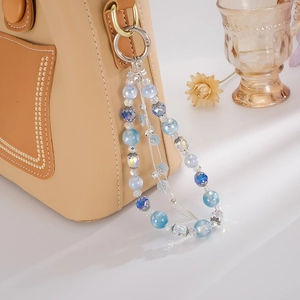 Luxury floral tassel phone charm with blue gradient beads on a brown leather bag