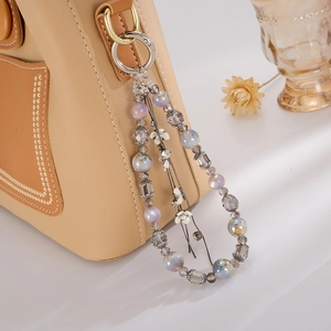 Floral tassel charm with iridescent beads and white flower detail on a leather bag