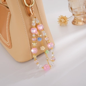 Detail showing beaded flower tassel with golden butterfly charms on a luxury beige handbag