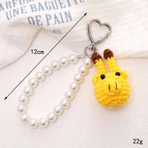 Handmade crochet giraffe keychain with white pearl beads and silver heart clasp