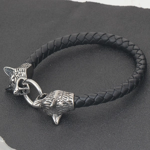 Makro-Detail des geflochtenen schwarzen Lederarmbands mit doppelten Wolfsköpfen
