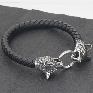 Detailansicht von zwei Wolfsköpfen an einem geflochtenen schwarzen Lederarmband für Herren