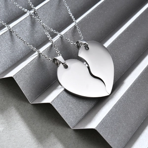 Polished stainless steel couple necklaces with 35mm split heart pendant on silver surface