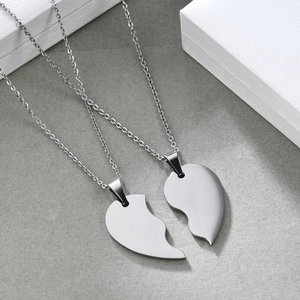 Polished stainless steel split heart couple necklace set on modern minimalist display