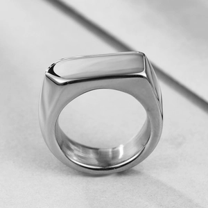 Close-up of a high-polished silver stainless steel signet ring on marble surface