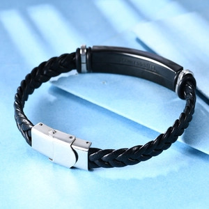 Detalle de pulsera de cuero trenzado negro con cierre de acero inoxidable y placa grabada