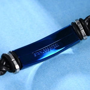 Vista macro de placa de acero inoxidable azul en pulsera de cuero trenzado negro