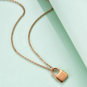 Collier avec pendentif cadenas en or rose 18K au fini poli sur fond géométrique menthe