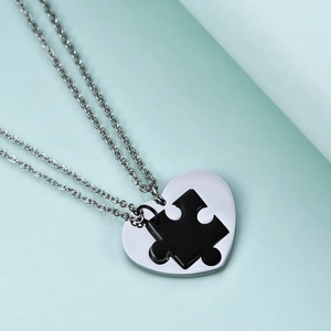 Detailed view of silver heart and black puzzle piece pendant set in polished steel