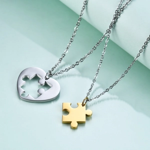 Detail shot of interlocking heart and puzzle piece necklaces in polished steel