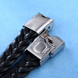 Detalle del cierre de acero inoxidable en una pulsera de cuero trenzado negro