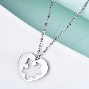 Detailed macro view of silver heart puzzle pendant in polished stainless steel finish