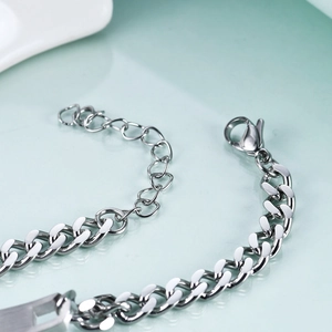 Close-up of silver curb chain bracelet with lobster clasp and extension on cyan mirror