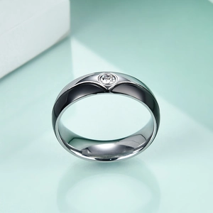 Macro detail of stainless steel couple ring featuring a black V-shape and inlaid crystal