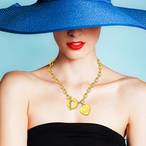 Dettaglio della collana OT dorata con ciondolo a cuore e incisioni sulla modella